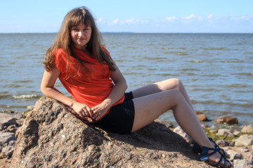 Girl sitting on a rock by the sea