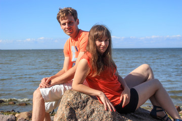 A couple of lovers sitting on boulders by the sea