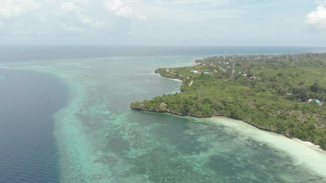Aerial: Flying over tropical beach turquoise water coral reef , Tomia island Wakatobi National Park Indonesia Maldives Polynesia white sand beach. Native cinelike D-log color profile