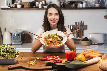 Beautiful young woman wearing apron cooking vegetables