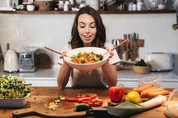 Beautiful young woman wearing apron cooking vegetables