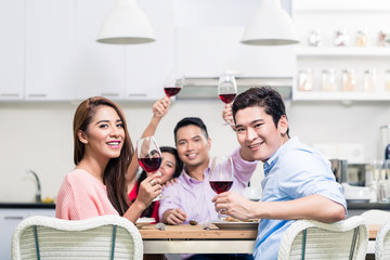 Portrait of happy friends holding red wine glasses