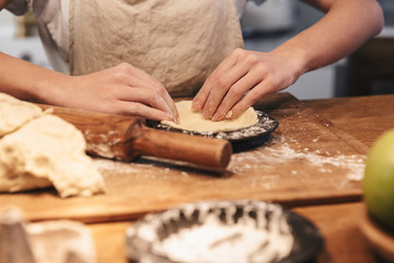 Close up of a woman wearing apron preparing dough