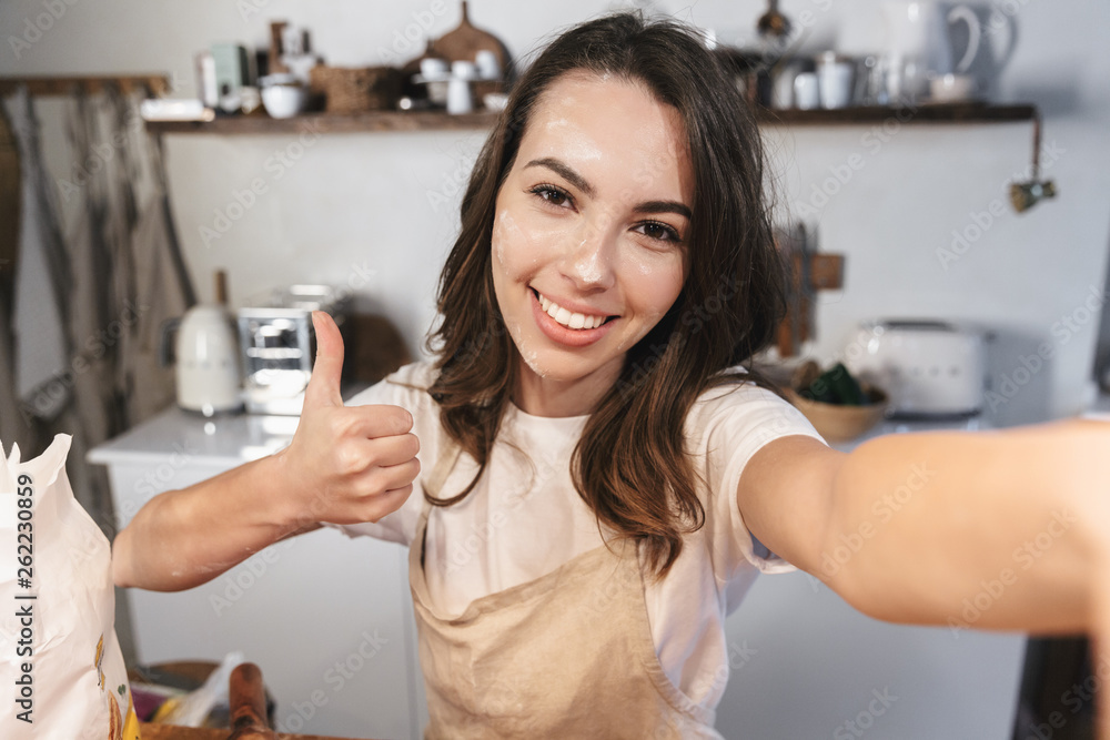 Poster Cheerful young girl covered with flour taking a selfie