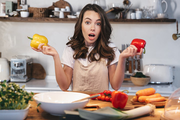Beautiful young woman wearing apron cooking vegetables