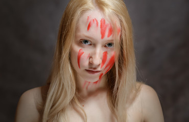Portrait of young woman with paint on her face on dark background.