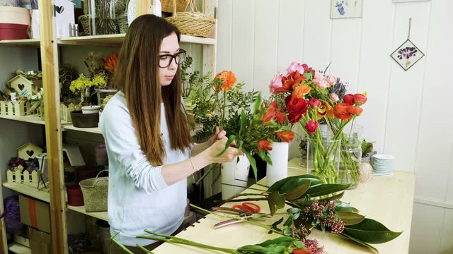Female florist in flower shop. Woman making a beautiful and stylish bouquet of fresh flowers in floral design studio. 4K