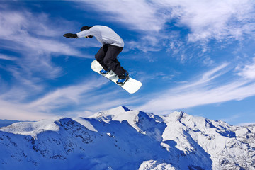 Naklejka na ściany i meble Snowboarder jumping through air with blue sky in background