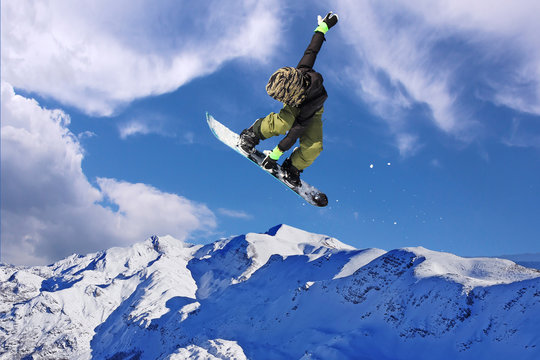 Snowboarder jumping through air with blue sky in background