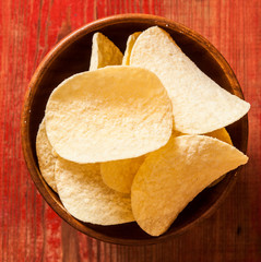Crispy potato chips in wooden bowl. Salted potato chips.