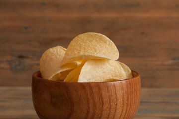 Crispy potato chips in wooden bowl. Salted potato chips.