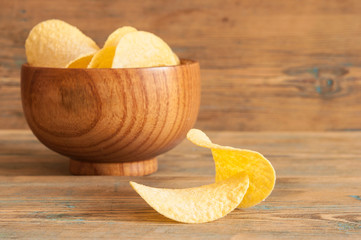 Crispy potato chips in wooden bowl. Salted potato chips.