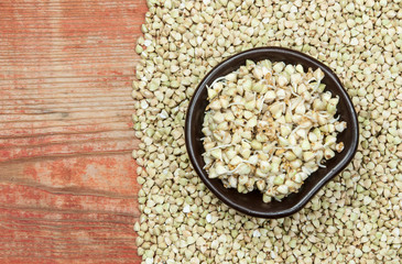 Buckwheat in a wooden bowl on an old wooden table, closeup view