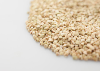 Raw green buckwheat pile on white background. Vegan or vegetarian food
