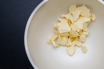 Pieces of butter are in a bowl for mixing in the preparation of cookies
