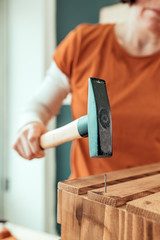 Female carpenter hammering nail into wooden crate