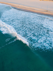 Fototapeta na wymiar Aerial view of breaking waves on the beach coastline.