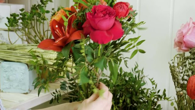 Female florist in flower shop. Woman making a beautiful and stylish bouquet of fresh flowers in floral design studio. 4K