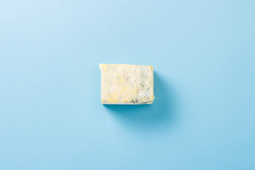 A piece of blue cheese on a blue background. Minimalism. Flat lay, top view.