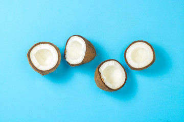 Obraz premium Broken coconut on a blue background. Concept of tropical fruits, vacation and travel, diet and weight loss. Flat lay, top view.
