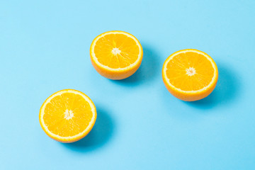 Half cut orange on a blue background. Concept of tropical fruits, vacation and travel, diet and weight loss.