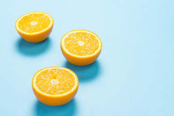 Half cut orange on a blue background. Concept of tropical fruits, vacation and travel, diet and weight loss.