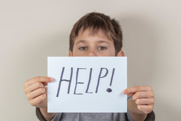 Help sign. Unhappy child holding paper with word Help
