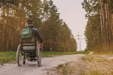 young disabled man in wheelchair walking park