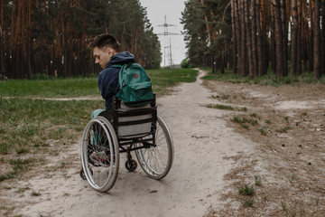 young disabled man in wheelchair walking park