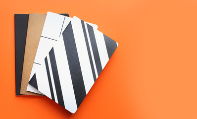 Back to school concept, school supplies, top view of colorful notebooks bright orange background