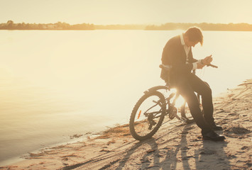 Fototapeta premium A man with a bicycle on a summer beach at sunset time