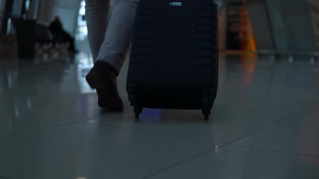 Close up shot of man legs with the baggage walking to the airport terminal.