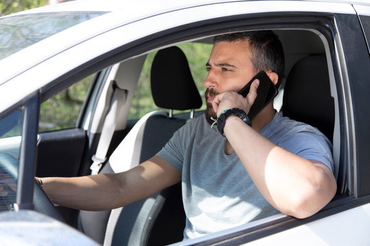 Man talking at mobile phone while driving a car.