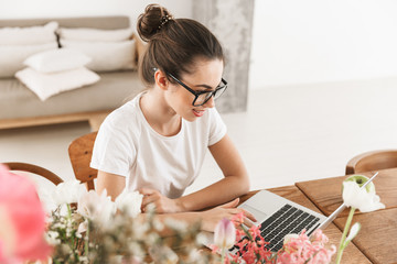 Beautiful young student girl sitting indoors using laptop computer.
