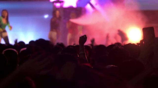 Crowd at concert in water festival   thailand,hd slow motion. Audiences dancing wet in front of big stage outdoor night concert hands up  with spray of water all around,strobe lights from stage .