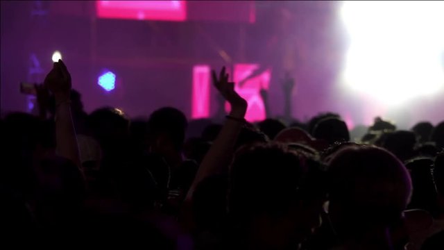 Crowd at concert in water festival   thailand,hd slow motion. Audiences dancing wet in front of big stage outdoor night concert hands up  with spray of water all around,strobe lights from stage .