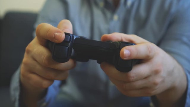 Man playing shooter video game on TV. Gamepad controller in hands.