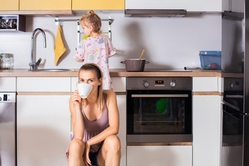 Mother is resting after making a lunch while her young daughter washing dishes