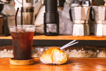 Cold coffee in plastic cup and dessert on the wood table.