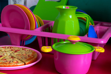 Colorful children's toy dishes and sliced pizza on the plate