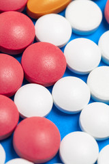 set of multi-colored tablets and capsules on a blue background