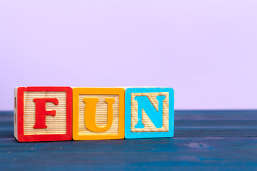 cube wooden block with alphabet building the word fun