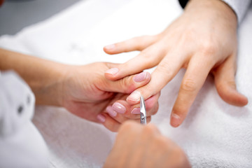 Obraz na płótnie Canvas Manicurist using cuticle scissors for nail treatment