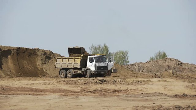 Bulldozer loading sand transportation truck on construction site. Construction equipment. Crawler bulldozer moving sand.