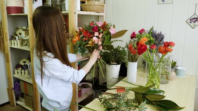 Female florist in flower shop. Woman making a beautiful and stylish bouquet of fresh flowers in floral design studio. 4K