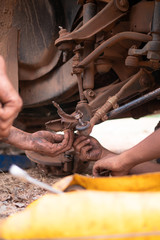 Hands of mechanic fixing wishbone control arm of the truck part to repair front wheel