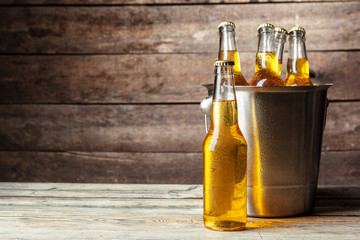 Cold bottles of beer in the bucket on the wooden background