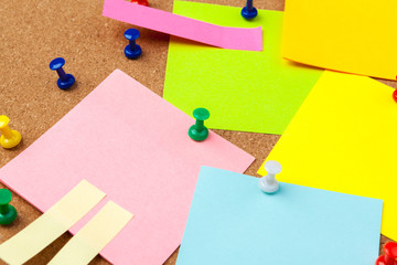 Cork board with several colorful blank notes with pins