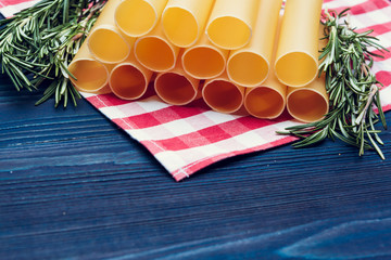 Raw italian pasta on dark blue wooden background, top view