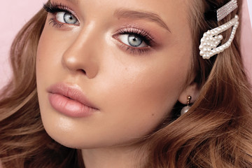 beautiful young woman with dark natural hair and tender makeup with pearl accessories